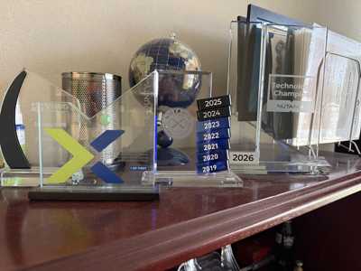 Nutanix awards on John Hamilton's shelf, including first 5,000 customers recognition and Technology Champion awards from 2019 through 2026.